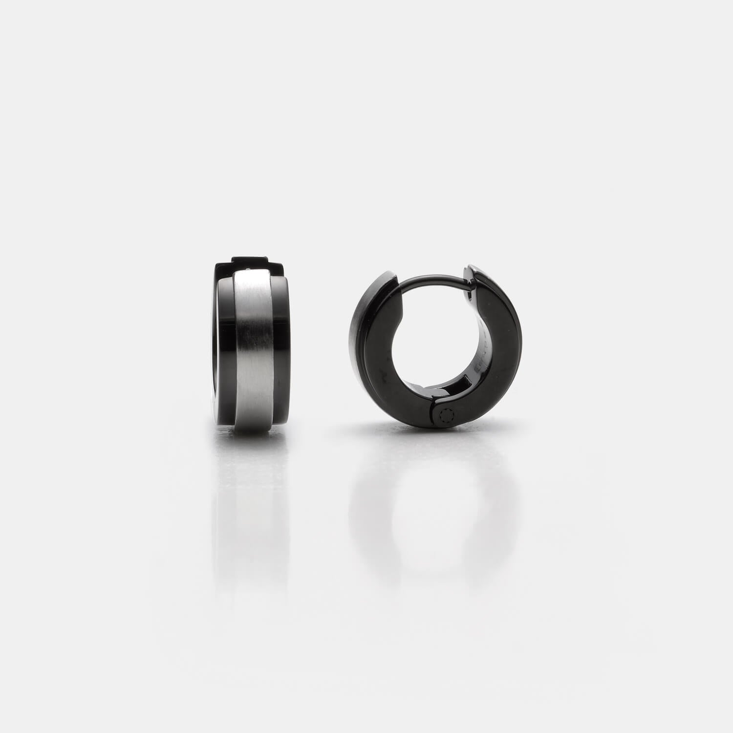 Ansicht von zwei schwarzen Edelstahl-Creolen mit silberfarbener Mittelfläche von MONOMANIA.