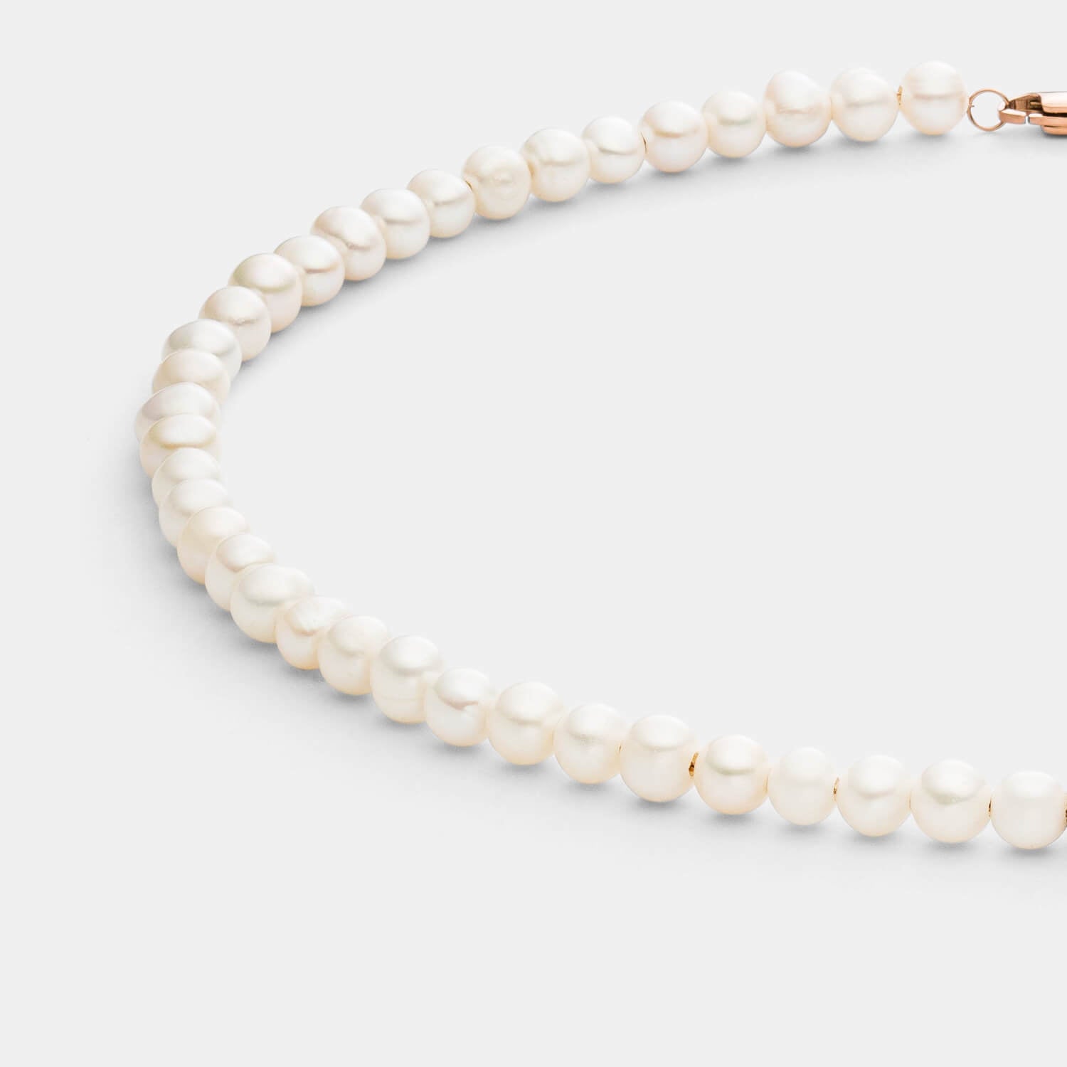 Detailansicht einer Perlenkette aus weißen Süßwasserperlen mit drei antiallergenen Edelstahlperlen.