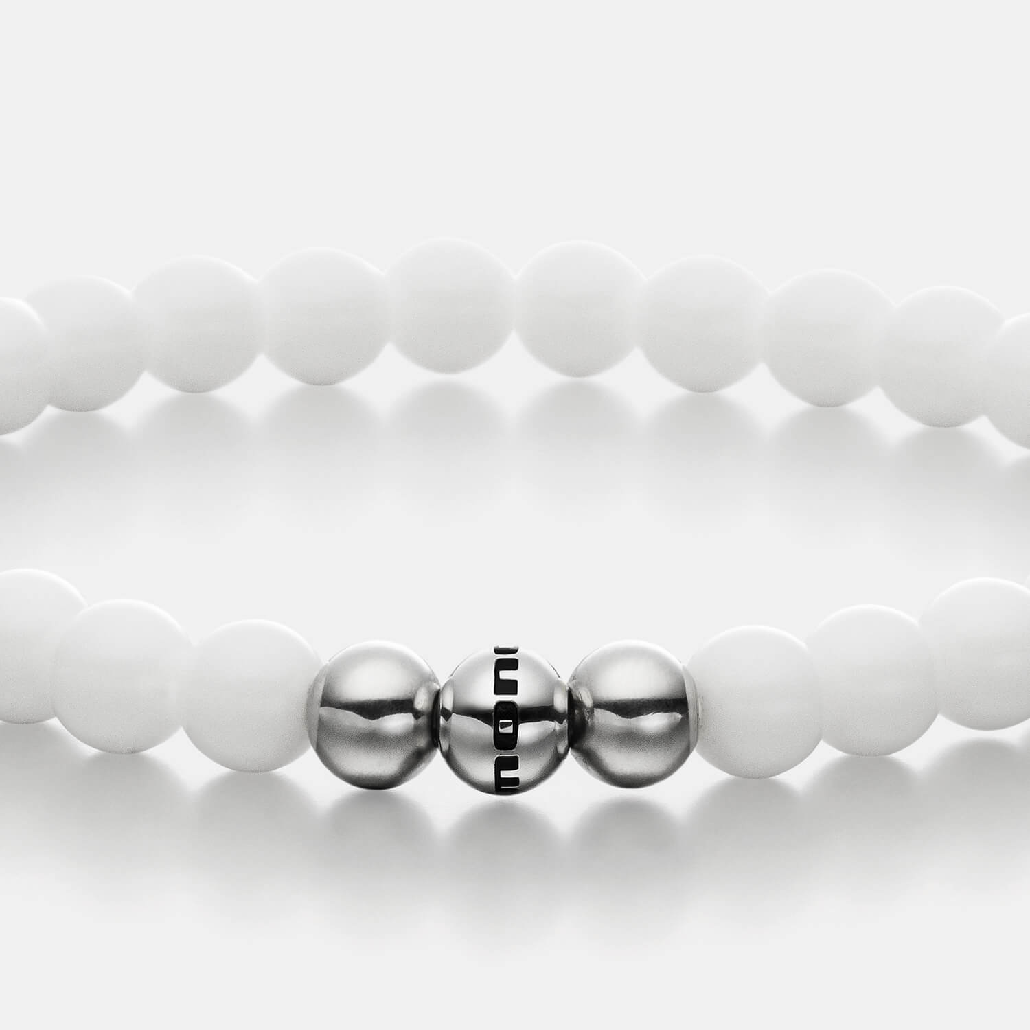 Gesamtansicht eines weißen Perlenarmbandes aus echten Bergkristallperlen mit drei antiallergenen Edelstahlperlen.