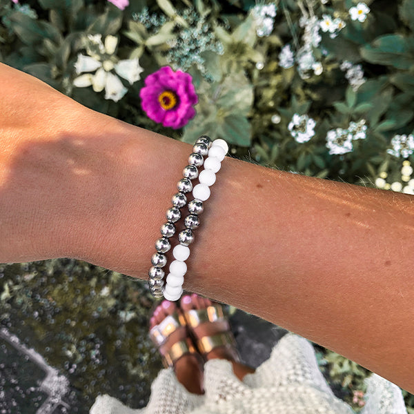 Gesamtansicht eines weißen Perlenarmbandes aus echten Achatperlen mit drei antiallergenen Edelstahlperlen.