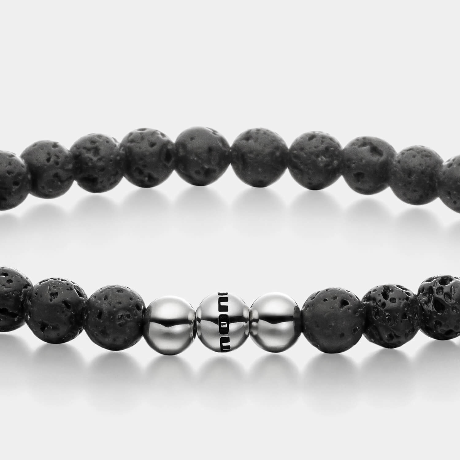 Gesamtansicht eines schwarzen Perlenarmbandes aus echten Lavaperlen mit drei antiallergenen Edelstahlperlen.