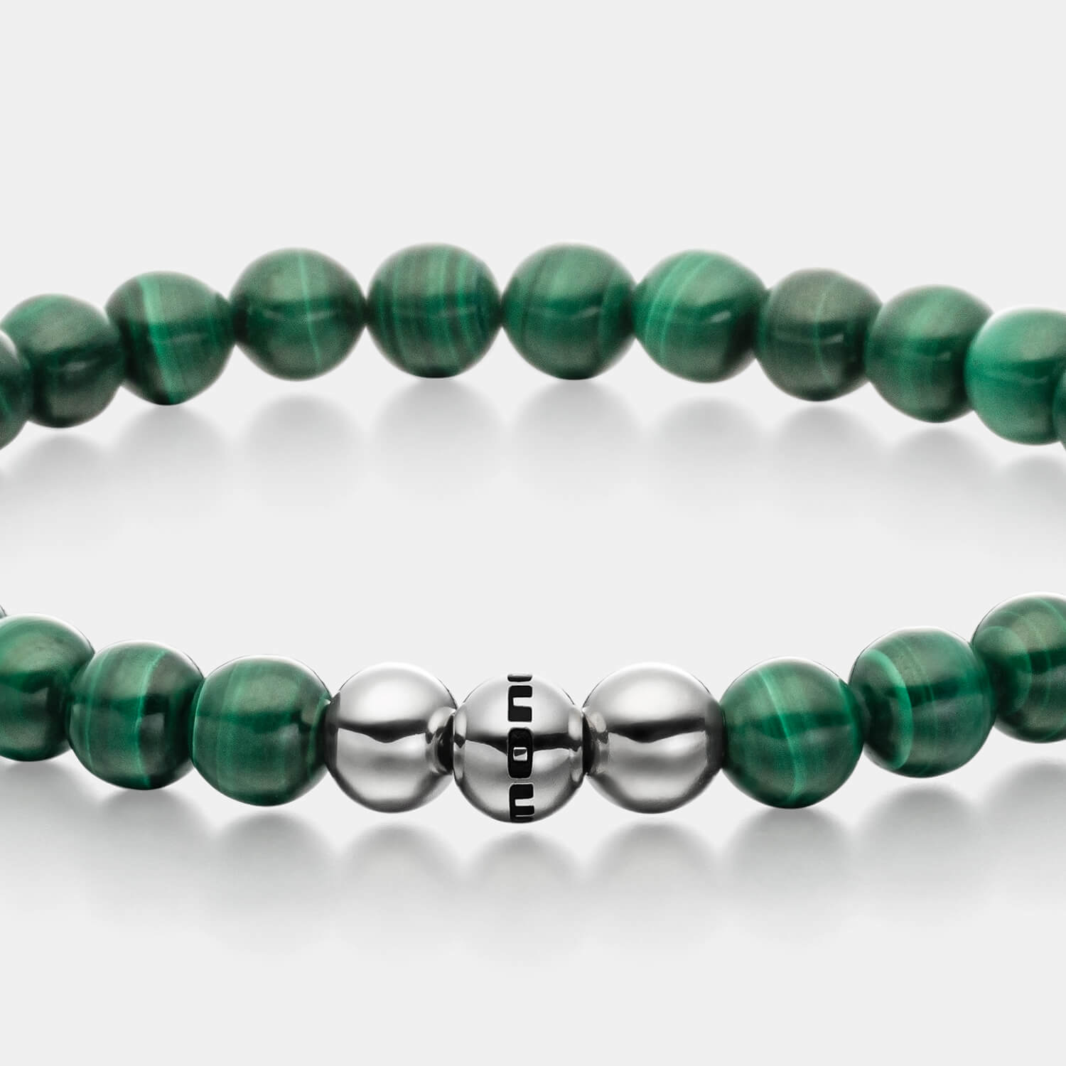 Gesamtansicht eines Perlenarmbandes aus echten grünen Malachitperlen mit drei antiallergenen Edelstahlperlen.