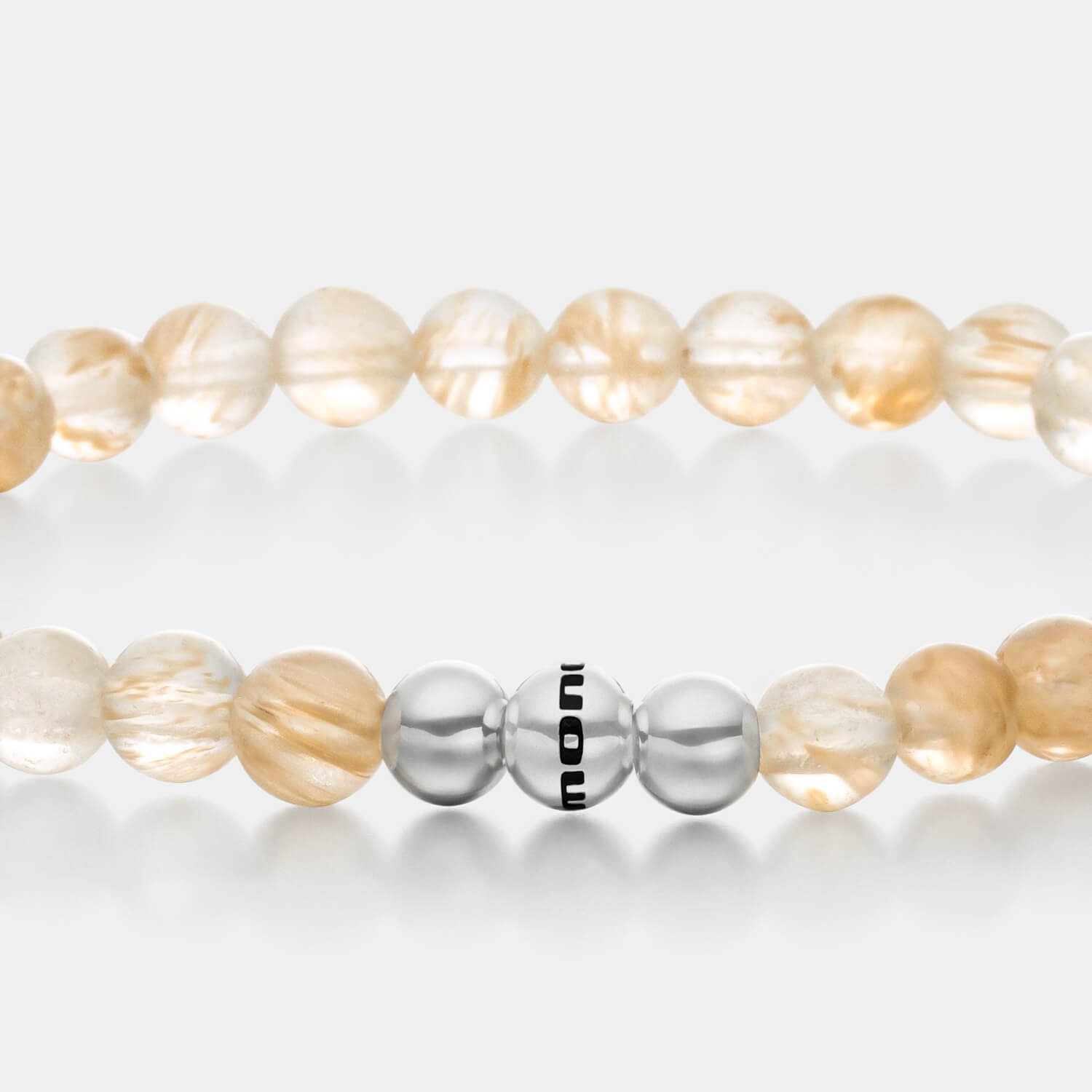 Gesamtansicht eines gelben Perlenarmbandes aus Rutilquarz mit drei polierten, antiallergenen Edelstahlperlen von MONOMANIA.