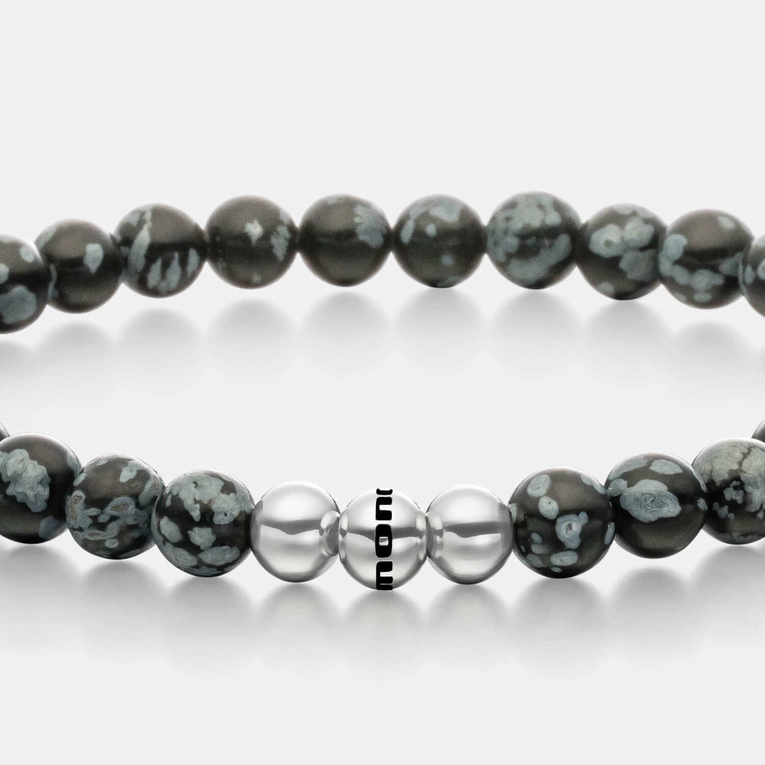 Gesamtansicht eines grauen Perlenarmbandes aus echten Schneeflocken-Obsidian-Perlen kombiniert mit drei antiallergenen Edelstahlperlen.