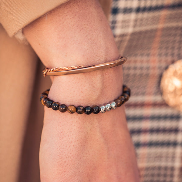 Gesamtansicht eines braunen Perlenarmbandes aus echten Tigerauge-Perlen mit drei antiallergenen Edelstahlperlen.