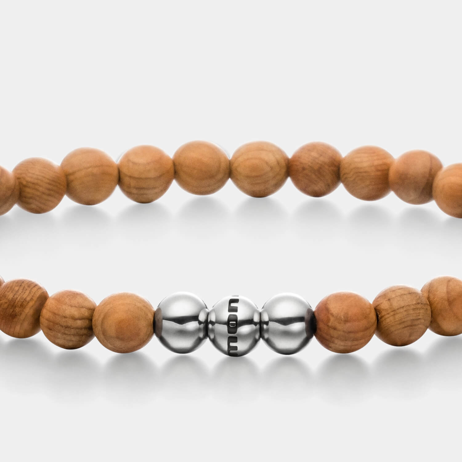 Gesamtansicht eines mittelbraunen Armbandes mit Perlen aus Holz und drei polierten, antiallergenen Edelstahlperlen.