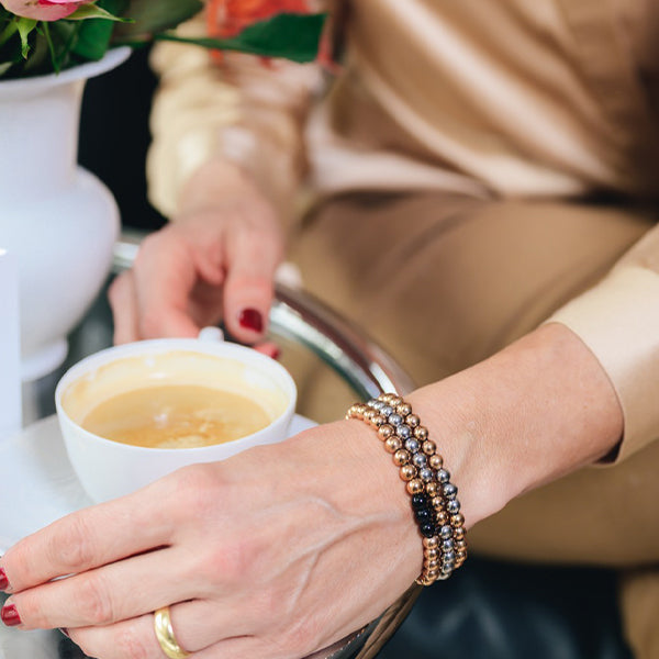 Gesamtansicht eines Perlenarmbandes aus silber-farbenen Edelstahlperlen mit drei roségold-farbenen Perlen.