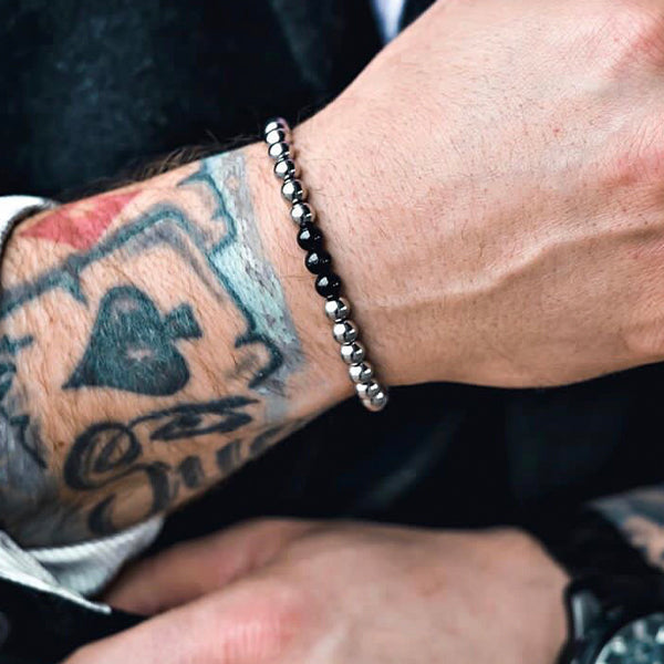 Gesamtansicht eines silberfarbenen Perlenarmbandes mit drei schwarz-beschichteten, antiallergenen Edelstahl-Perlen.
