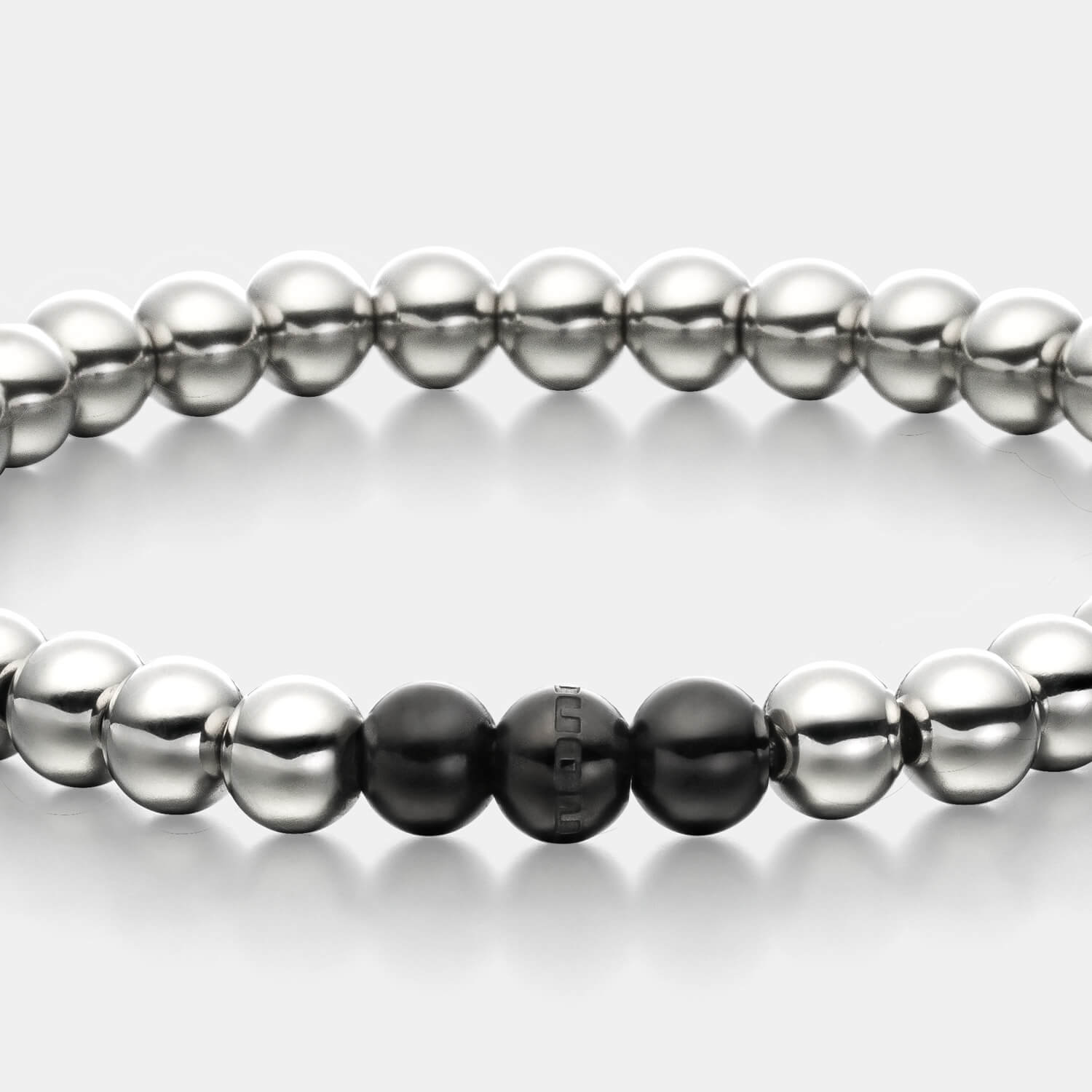Gesamtansicht eines silberfarbenen Perlenarmbandes mit drei schwarz-beschichteten, antiallergenen Edelstahl-Perlen.