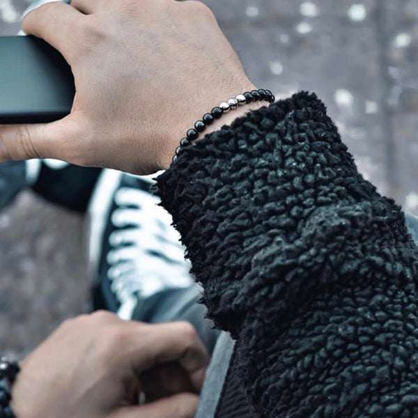 Gesamtansicht eines schwarzen Perlenarmbandes aus schwarz-beschichteten, antiallergenen Edelstahl-Perlen mit drei silberfarbenen Edelstahlperlen.