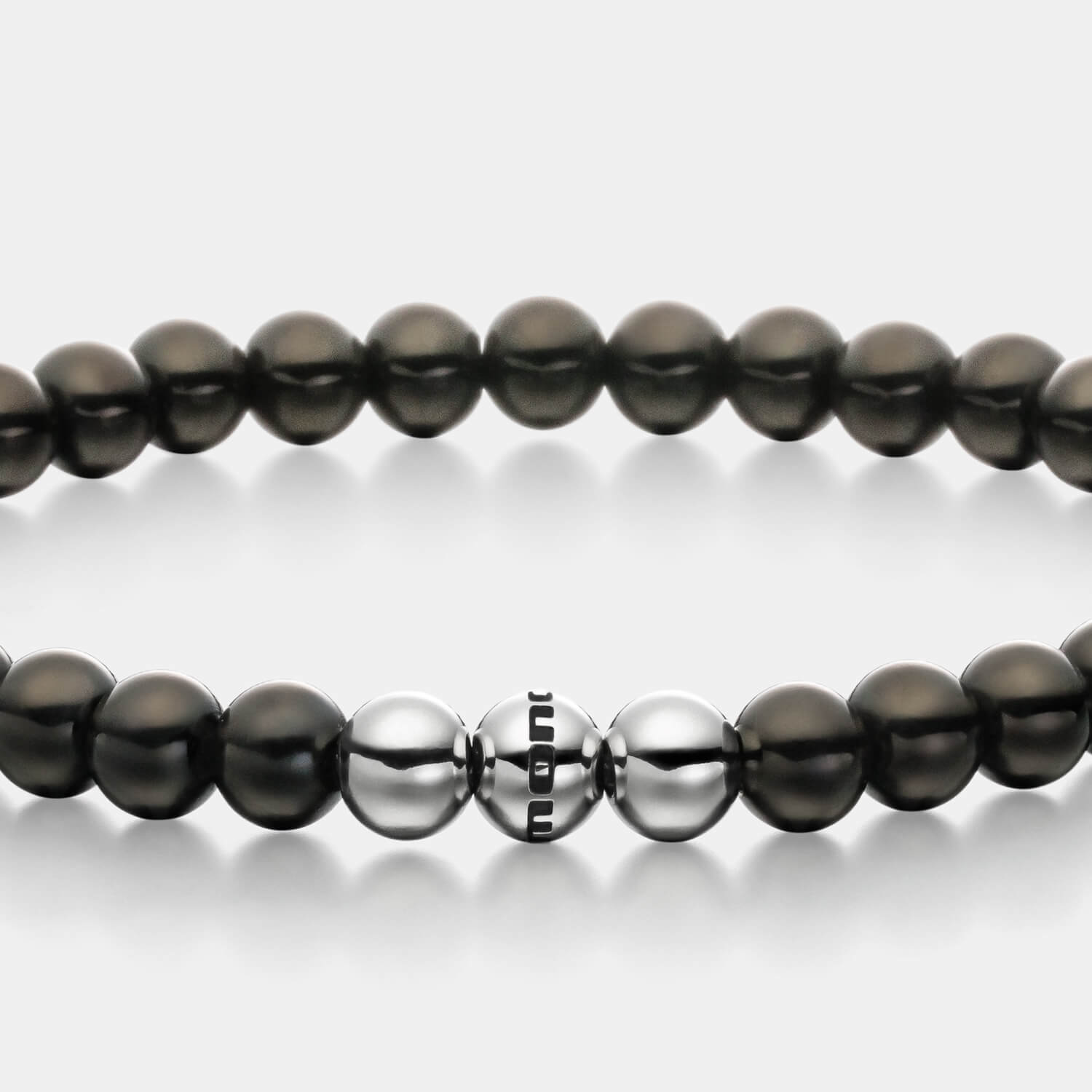 Gesamtansicht eines schwarzen Perlenarmbandes aus schwarz-beschichteten, antiallergenen Edelstahl-Perlen mit drei silberfarbenen Edelstahlperlen.