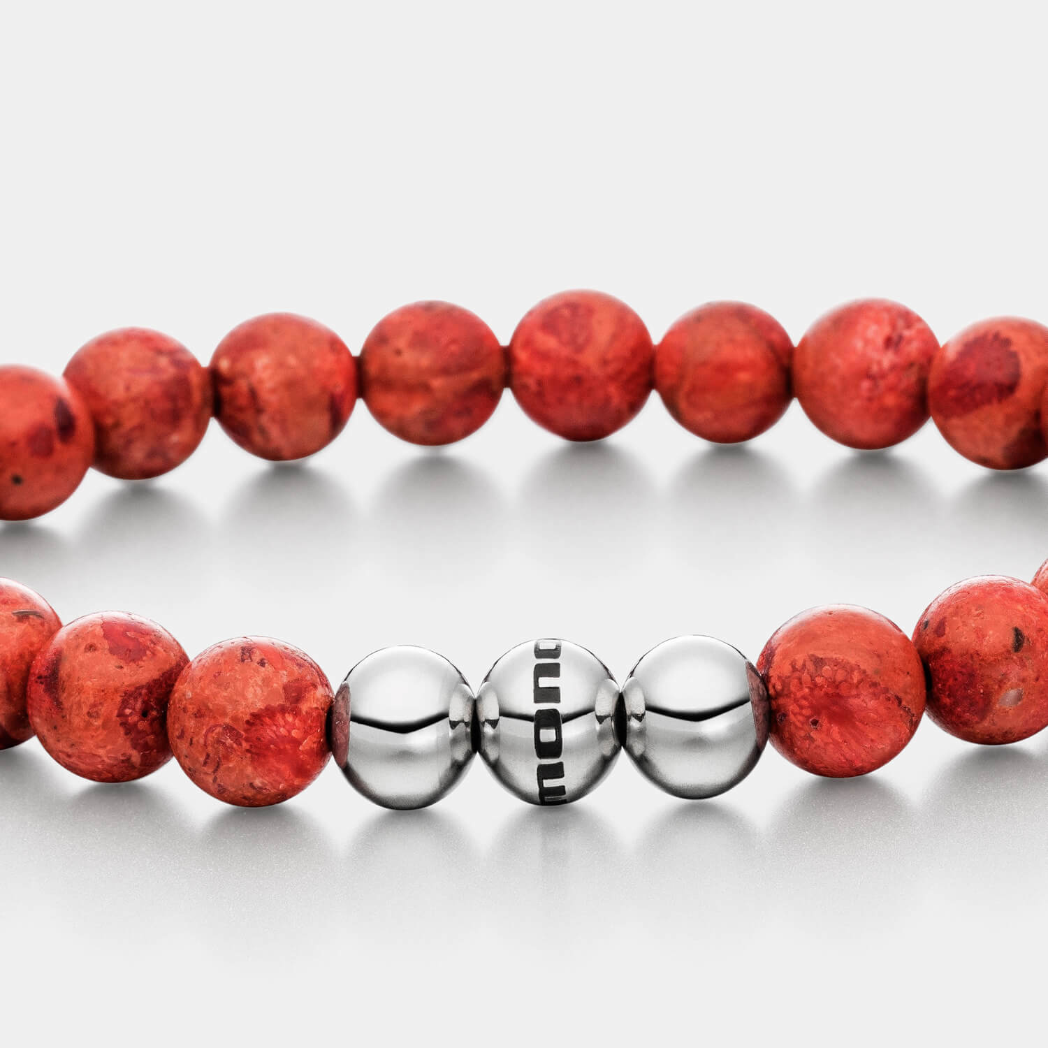 Gesamtansicht eines roten Perlenarmbandes mit großen Perlen aus rekonstruierter Koralle mit drei polierten, antiallergenen Edelstahlperlen.