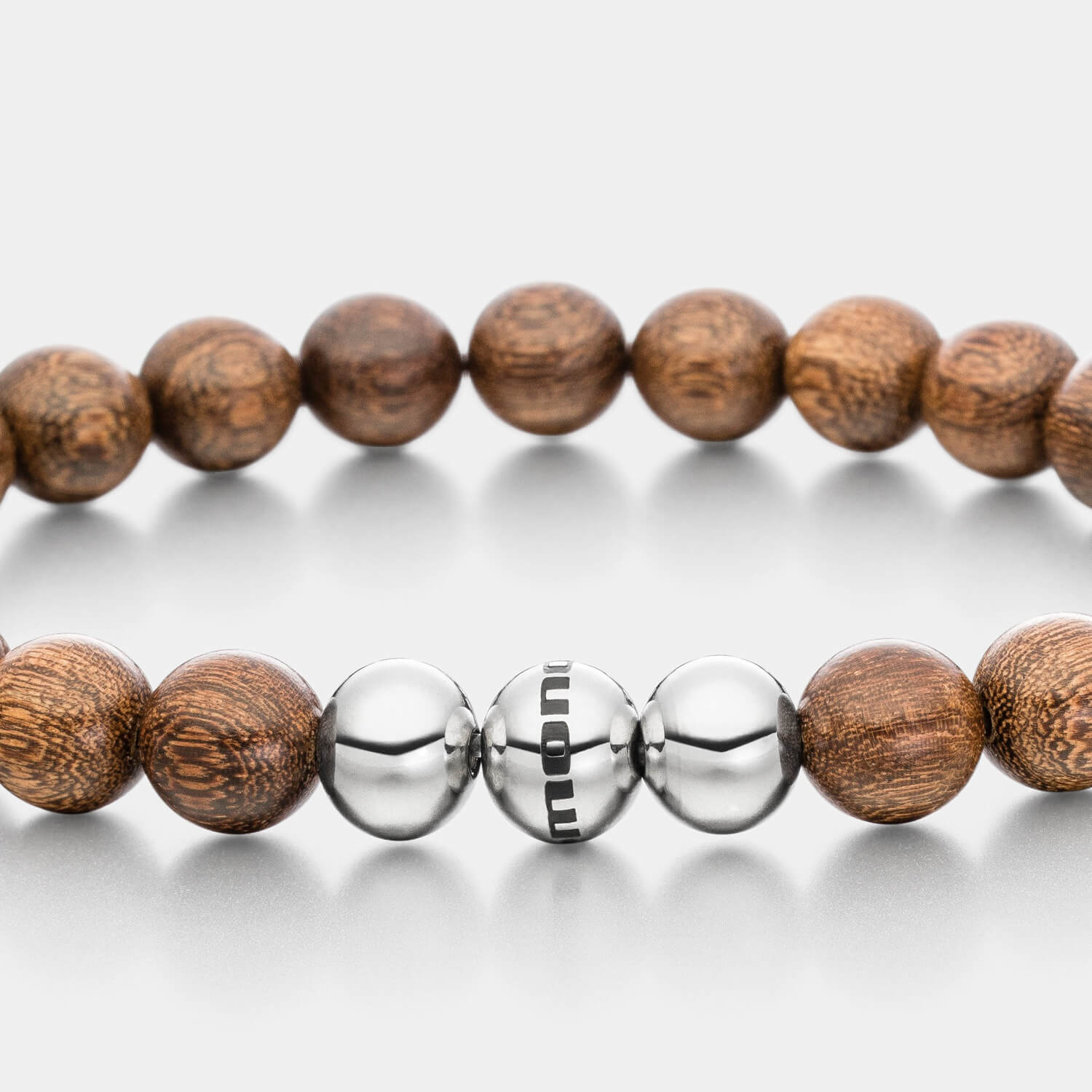 Gesamtansicht eines maskulinen, braunen Perlenarmbandes aus echten Holzperlen aus Nussbaumholz mit drei antiallergenen Edelstahlperlen.