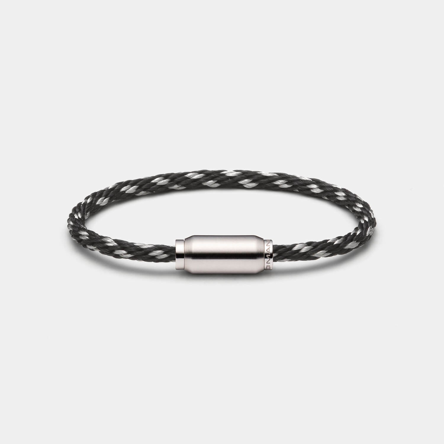 Gesamtansicht eines schicken Armbandes: Kombination aus gebürsteter, zylinderförmiger Hülse mit einem schwarzen Edelstahl-Materialmixband von MONOMANIA.