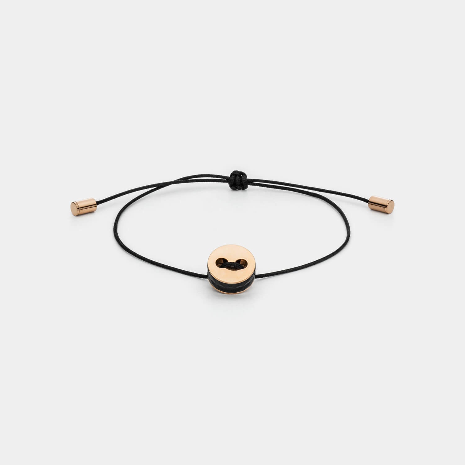 Gesamtansicht eines größenverstellbaren, schwarzen Armbandes mit roséfarbenem Anhänger aus antiallergenem Edelstahl von MONOMANIA.