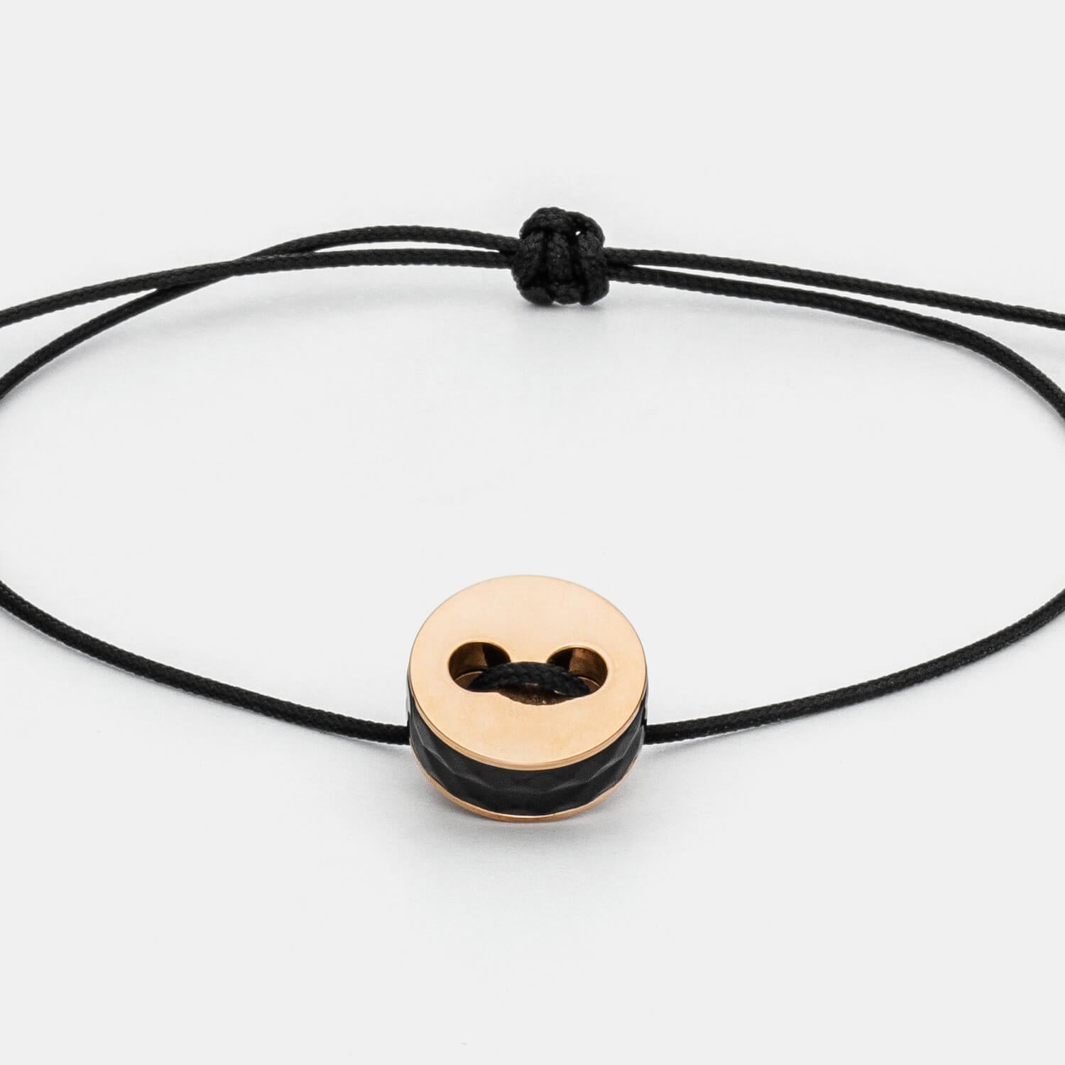 Gesamtansicht eines größenverstellbaren, schwarzen Armbandes mit roséfarbenem Anhänger aus antiallergenem Edelstahl von MONOMANIA.