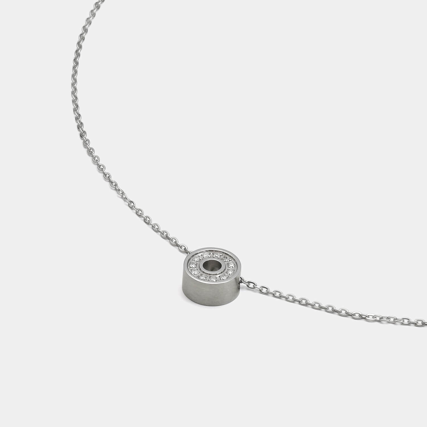 Detailansicht eines runden Edelstahl-Anhängers mit 11 gesetzten, echten Diamanten an einer zarten Kette mit Karabinerverschluss von MONOMANIA.