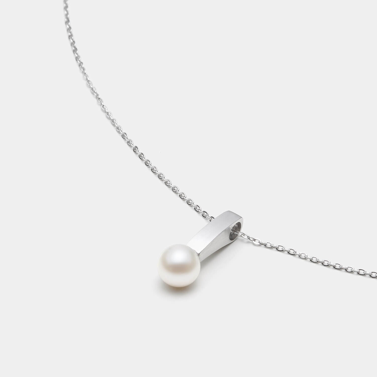 Perspektivische Detailansicht des Pearl´s Kiss Anhängers aus antiallergenem Edelstahl mit Süßwasserperle an einer eleganten Kette mit Karabinerverschluss von MONOMANIA.