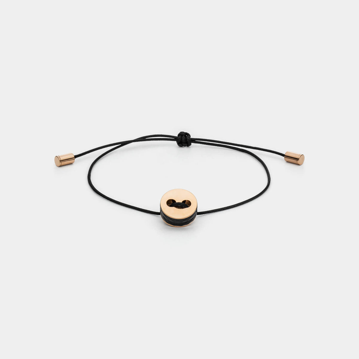 Gesamtansicht eines größenverstellbaren, schwarzen Armbandes mit roséfarbenem Anhänger aus antiallergenem Edelstahl von MONOMANIA.