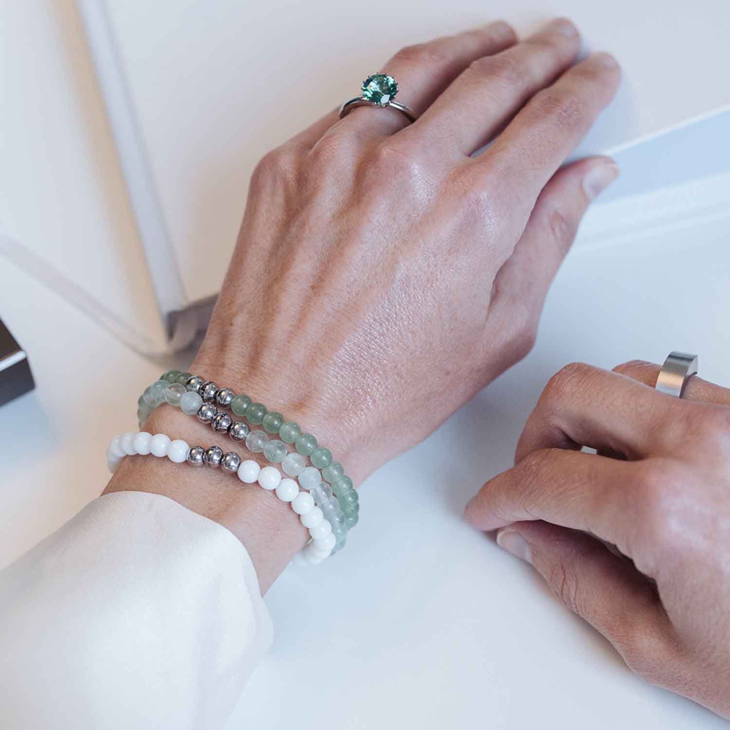 Gesamtansicht eines weißen Perlenarmbandes aus echten Achatperlen mit drei antiallergenen Edelstahlperlen.