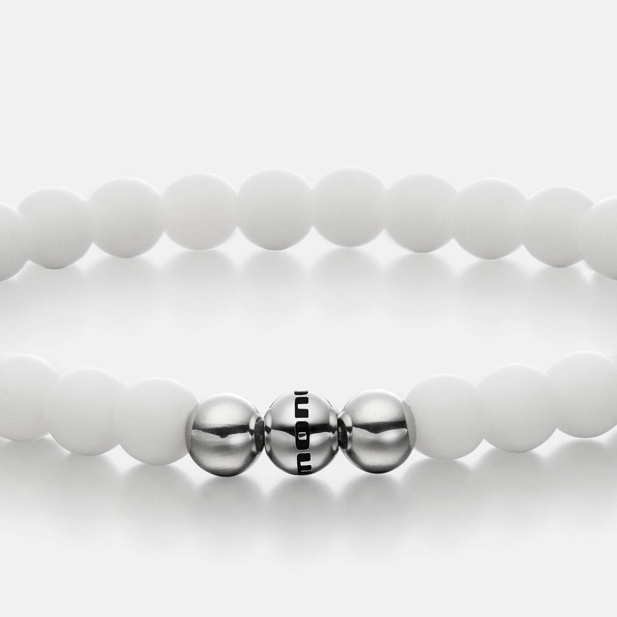 Gesamtansicht eines weißen Perlenarmbandes aus echten Achatperlen mit drei antiallergenen Edelstahlperlen.