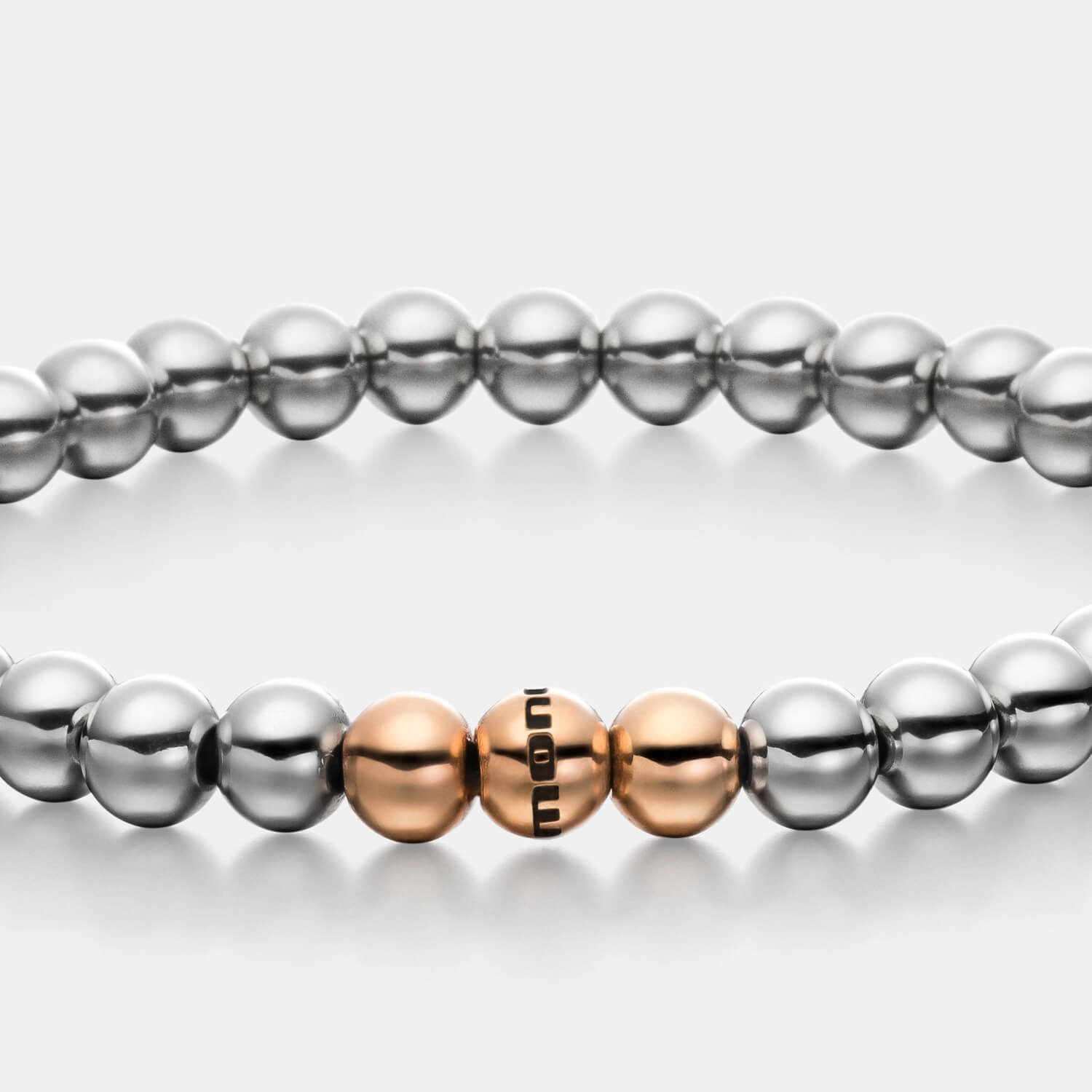 Gesamtansicht eines Perlenarmbandes aus silber-farbenen Edelstahlperlen mit drei roségold-farbenen Perlen.