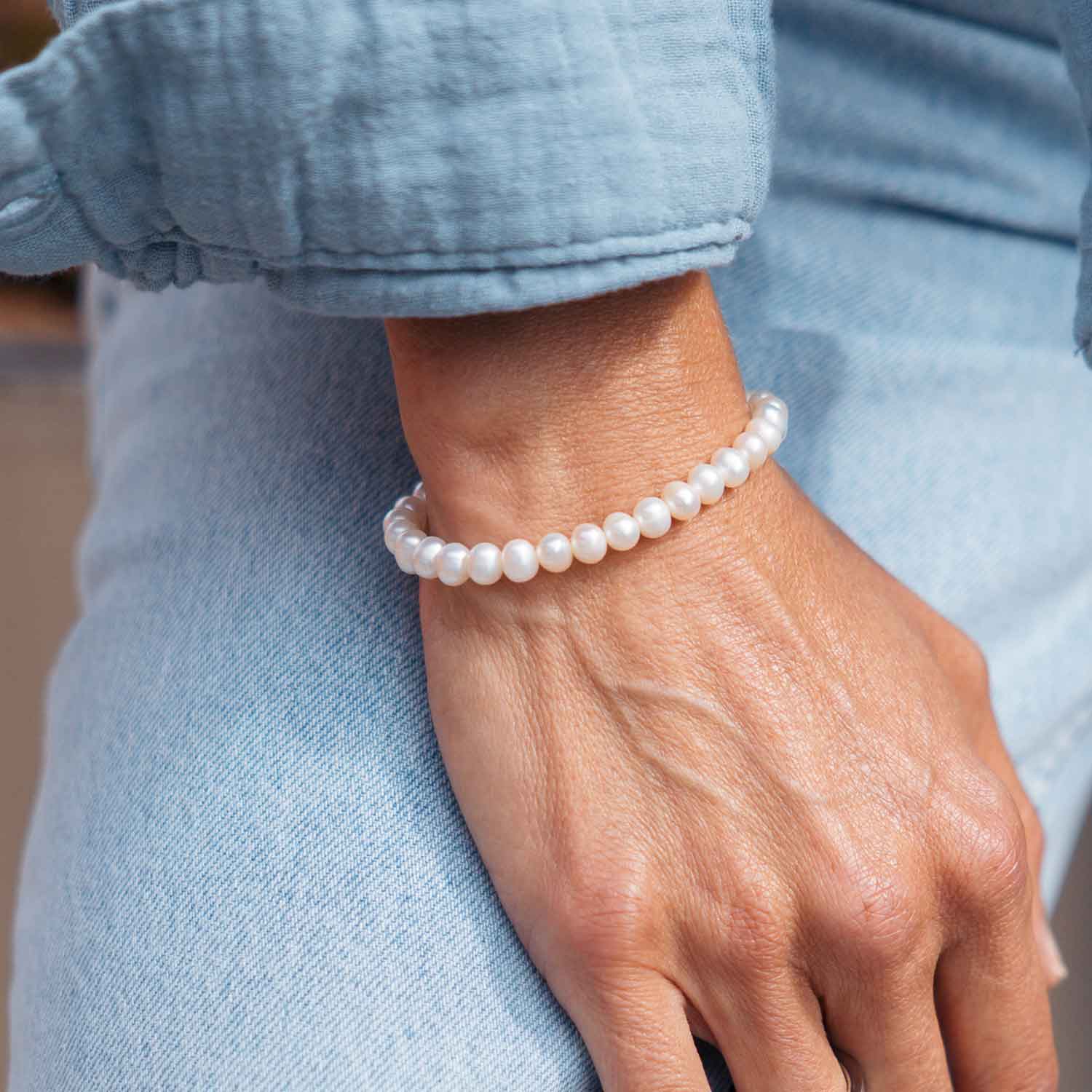 Gesamtansicht eines weißen Perlenarmbandes aus echten Süßwasserperlen mit drei antiallergenen Edelstahlperlen.(109 Zeichen inkl L)