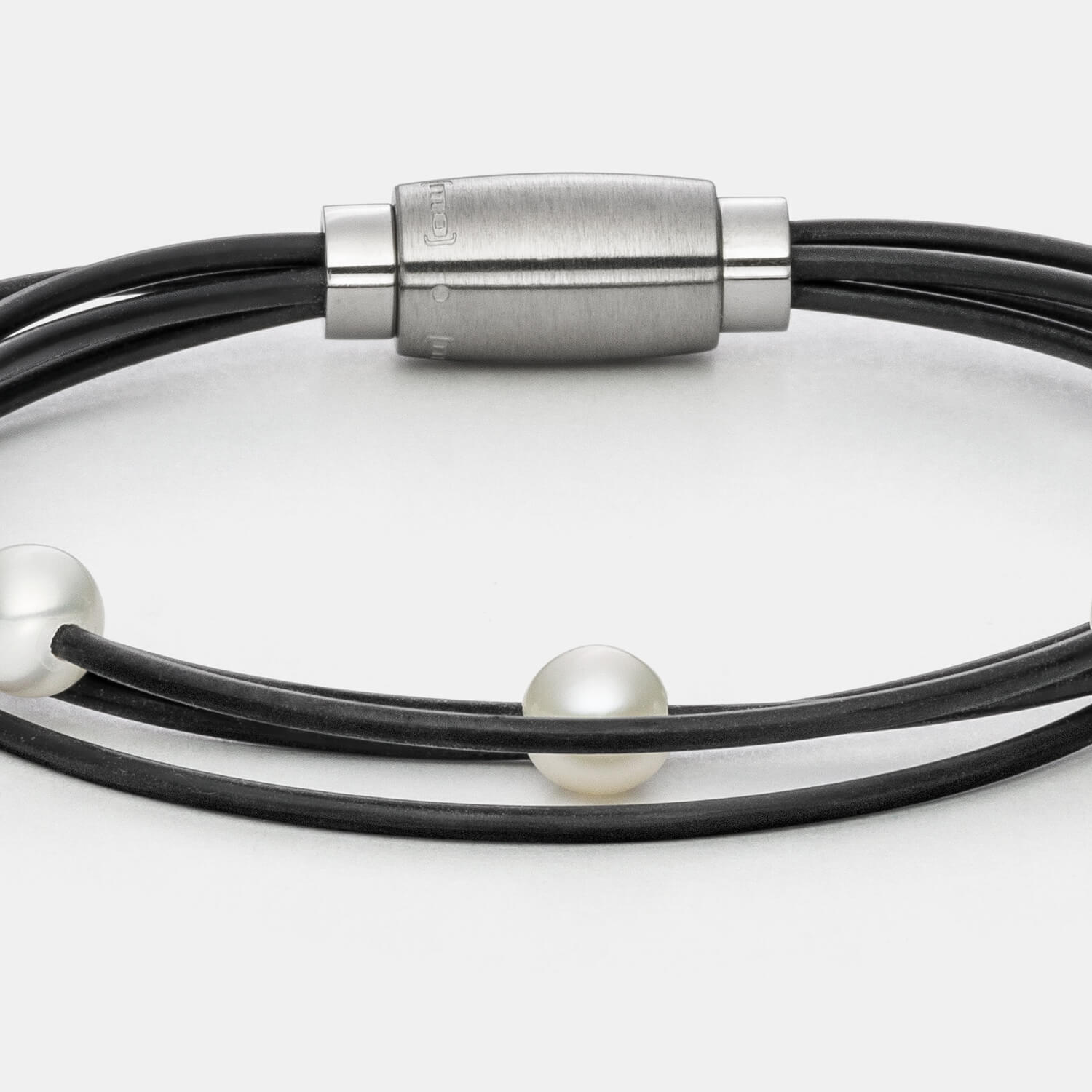 Gesamtansicht des modernen Armbandes mit echten, weißen Süßwasserperlen auf einem vierreihigen Kautschukband von MONOMANIA.