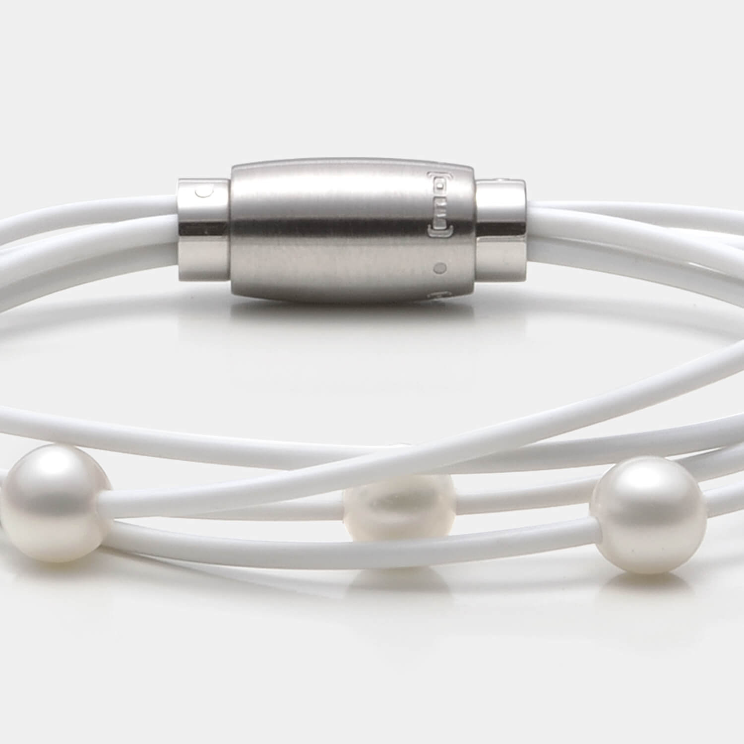 Gesamtansicht des edlen Armbandes mit echten, weißen Süßwasserperlen auf einem vierreihigen, weißen Kautschukband von MONOMANIA.