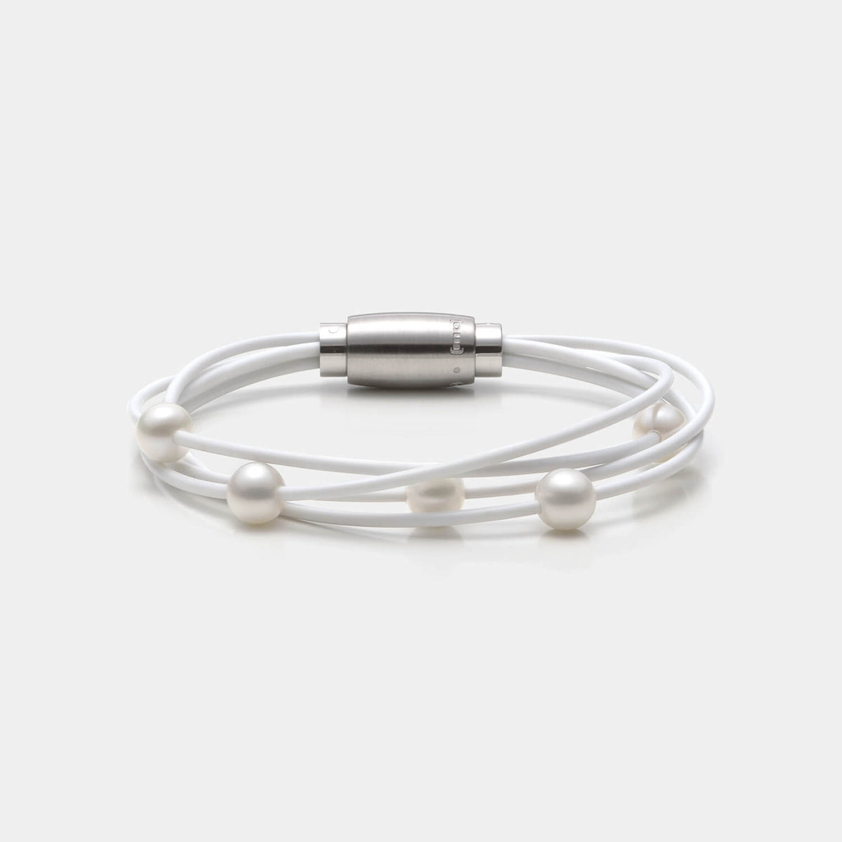 Gesamtansicht des edlen Armbandes mit echten, weißen Süßwasserperlen auf einem vierreihigen, weißen Kautschukband von MONOMANIA.