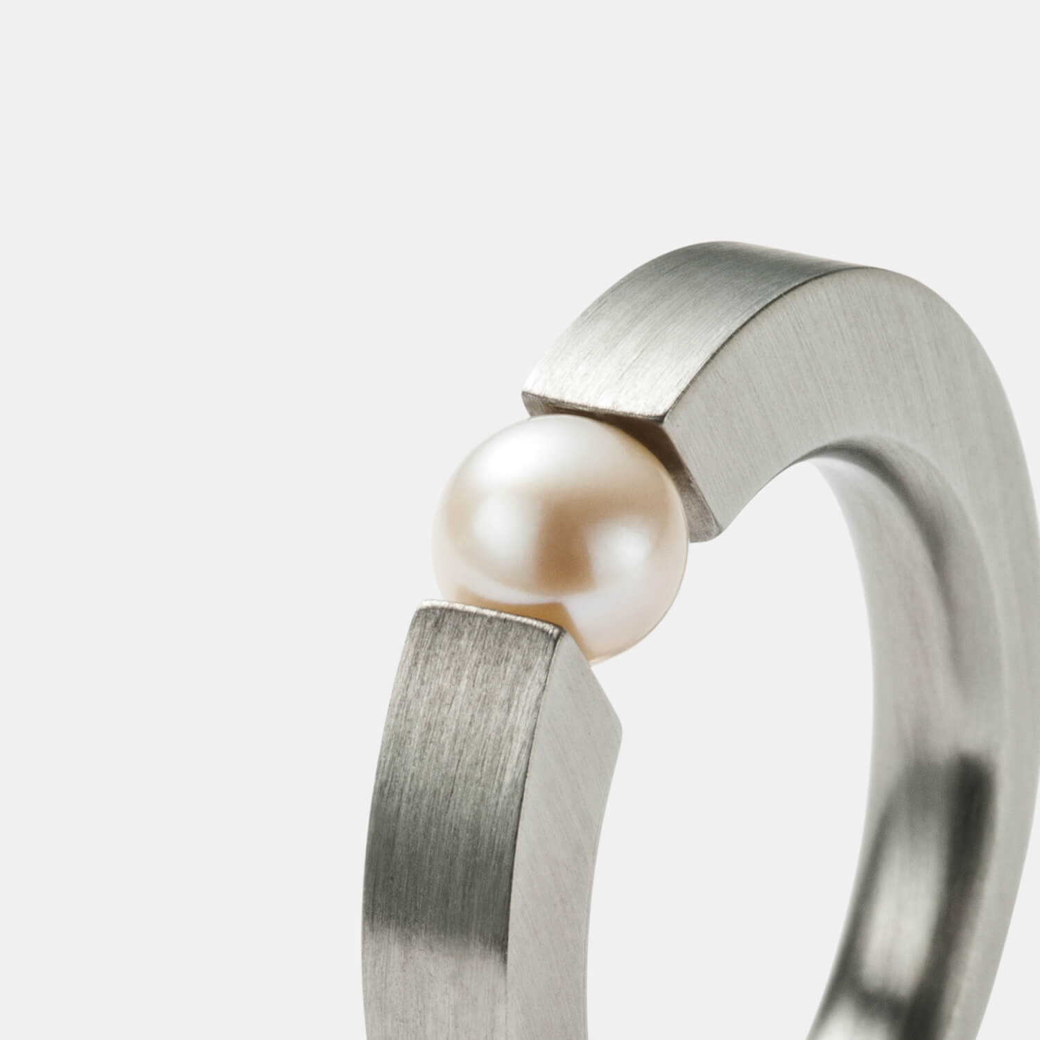 Gesamtansicht eines sehr edlen Spannrings aus gebürstetem, antiallergenen Edelstahl mit einer eingespannten, echten Süßwasserperle im klassischen Weißton von MONOMANIA.
