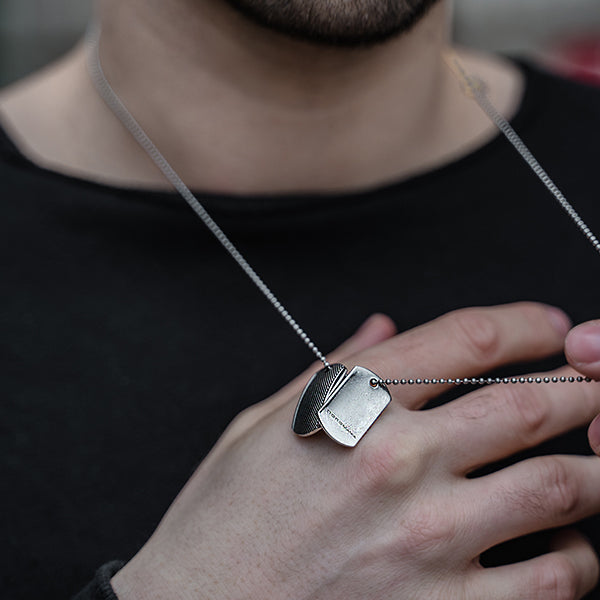 Detailansicht eines silberfarbenen Dog Tag Anhänger-Sets aus antiallergenem Edelstahl mit Punkterelief an einer Kugelkette.