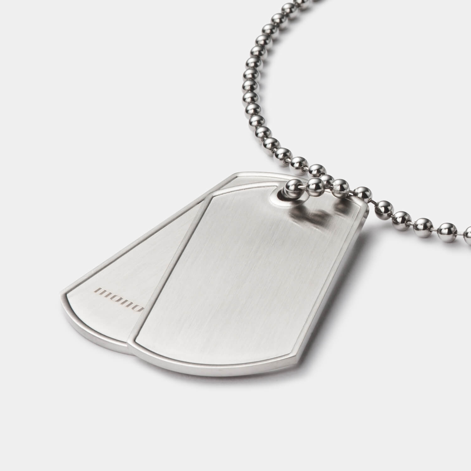 Im Detail: Zwei gebürstete Dog Tags (mit und ohne Logo) aus antiallergenem Edelstahl an einer Kugelkette mit Bajonettverschluss von MONOMANIA.