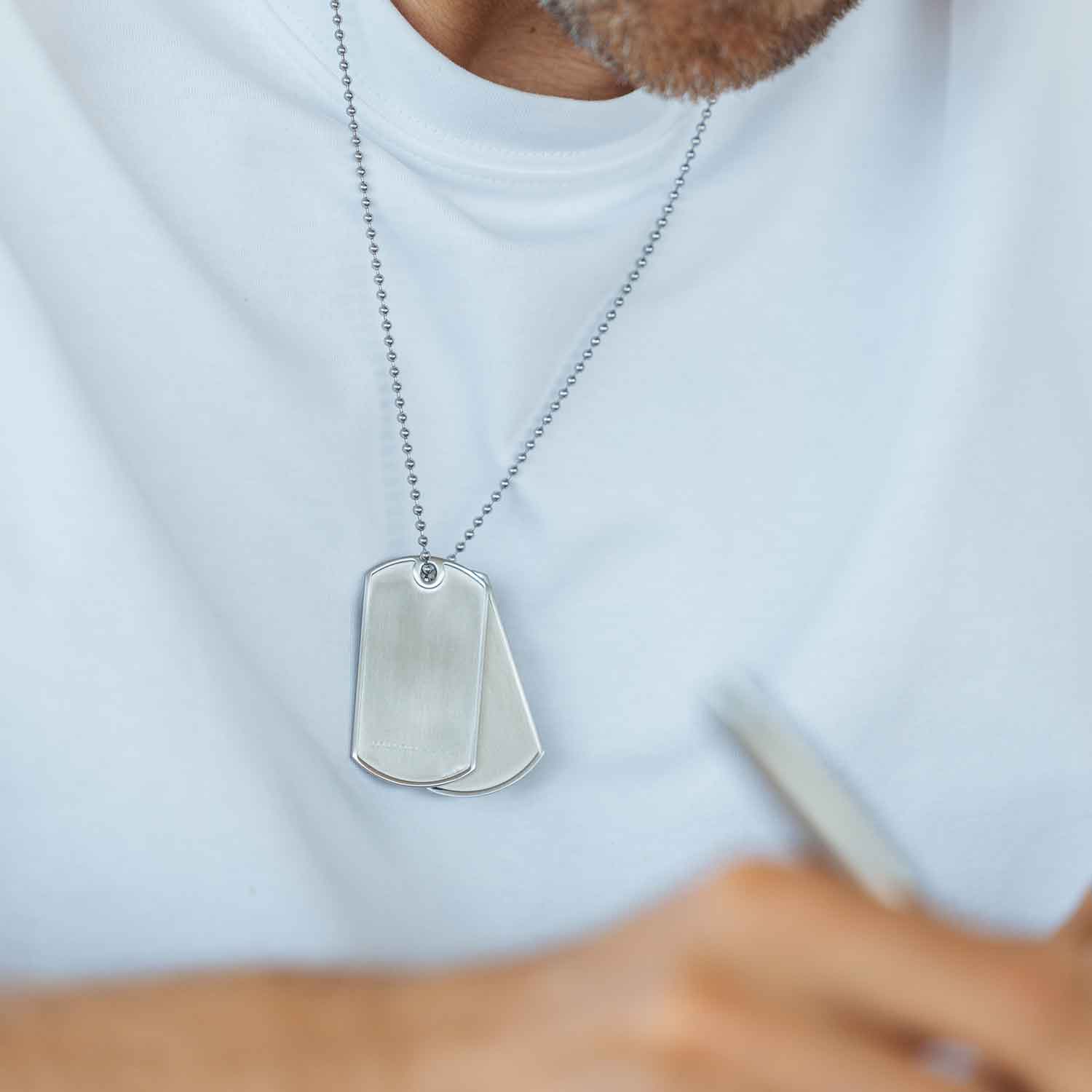 Im Detail: Zwei gebürstete Dog Tags (mit und ohne Logo) aus antiallergenem Edelstahl an einer Kugelkette mit Bajonettverschluss von MONOMANIA.