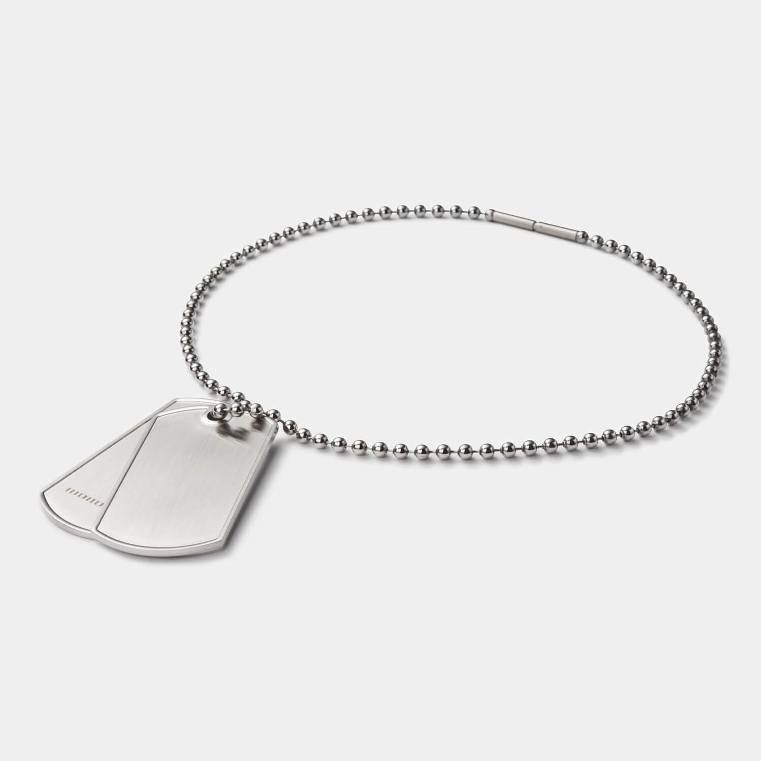 Im Detail: Zwei gebürstete Dog Tags (mit und ohne Logo) aus antiallergenem Edelstahl an einer Kugelkette mit Bajonettverschluss von MONOMANIA.