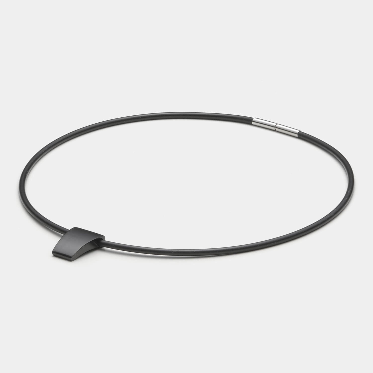 Detailansicht eines schlichten, schwarzen Anhängers aus antiallergenem Edelstahl an einem schwarzen Kautschukband von MONOMANIA.