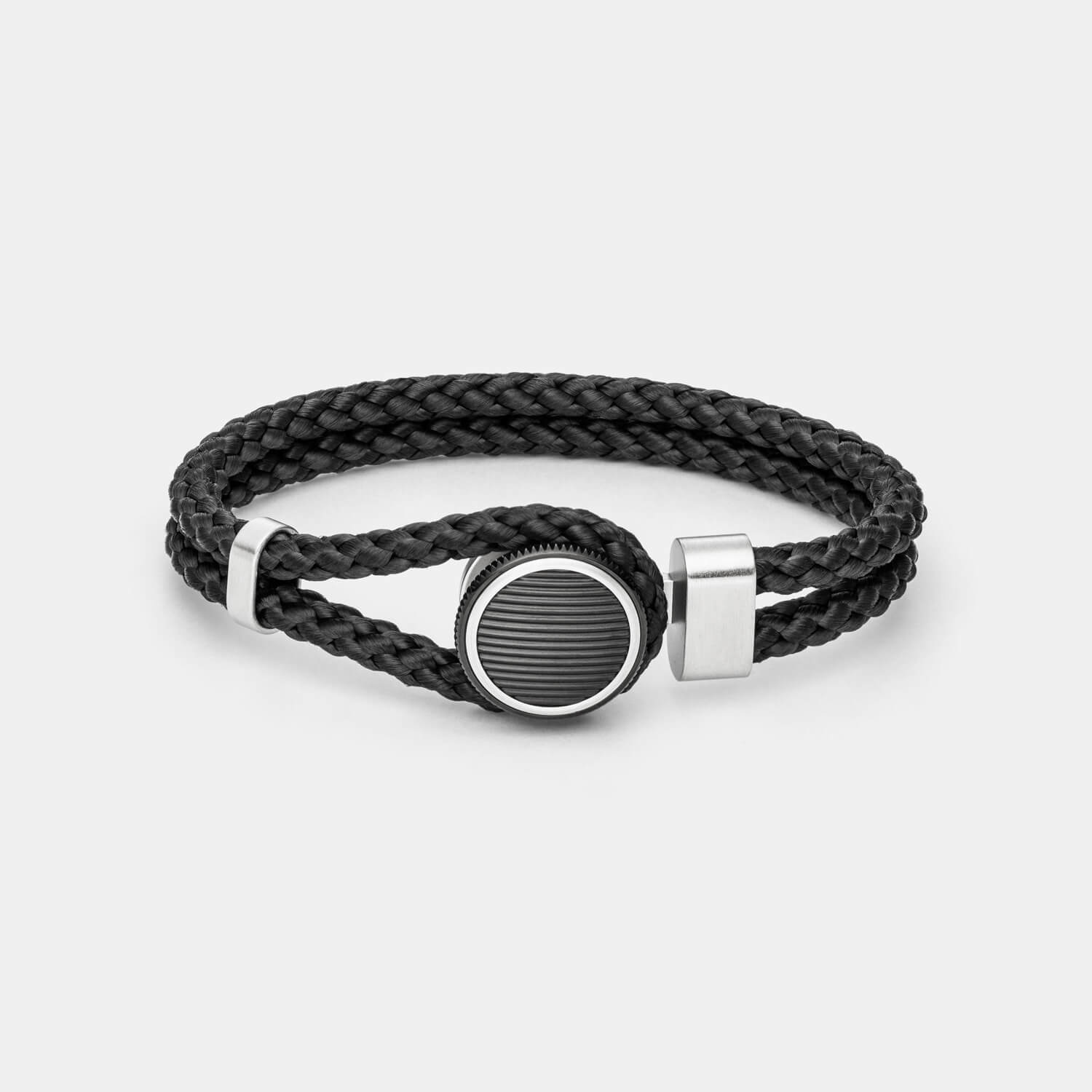 Gesamtansicht eines Armbandes mit schwarzem, geflochtenen Textil und rundem, schwarzen Verschluss von MONOMANIA.