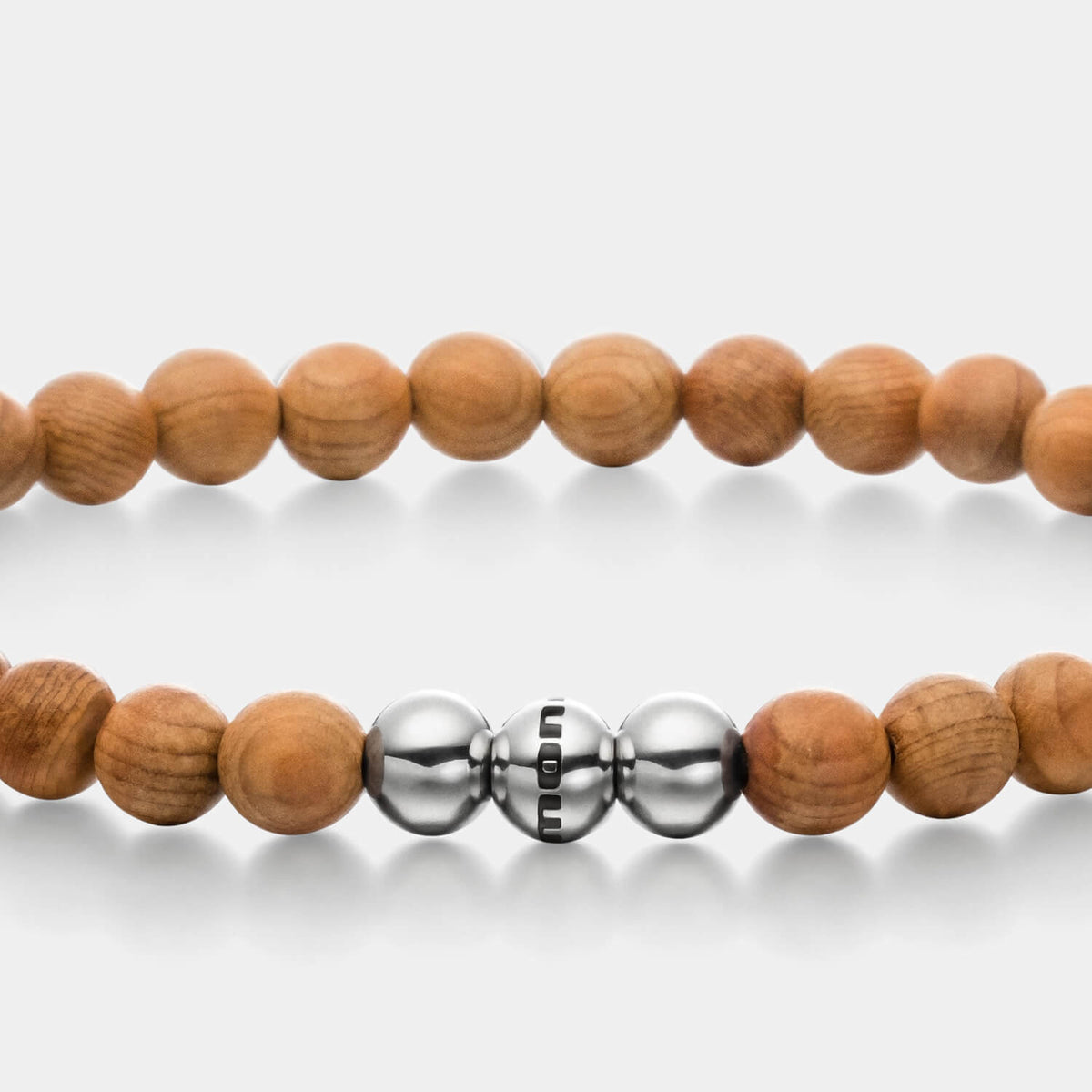 Gesamtansicht eines mittelbraunen Armbandes mit Perlen aus Holz und drei polierten, antiallergenen Edelstahlperlen.