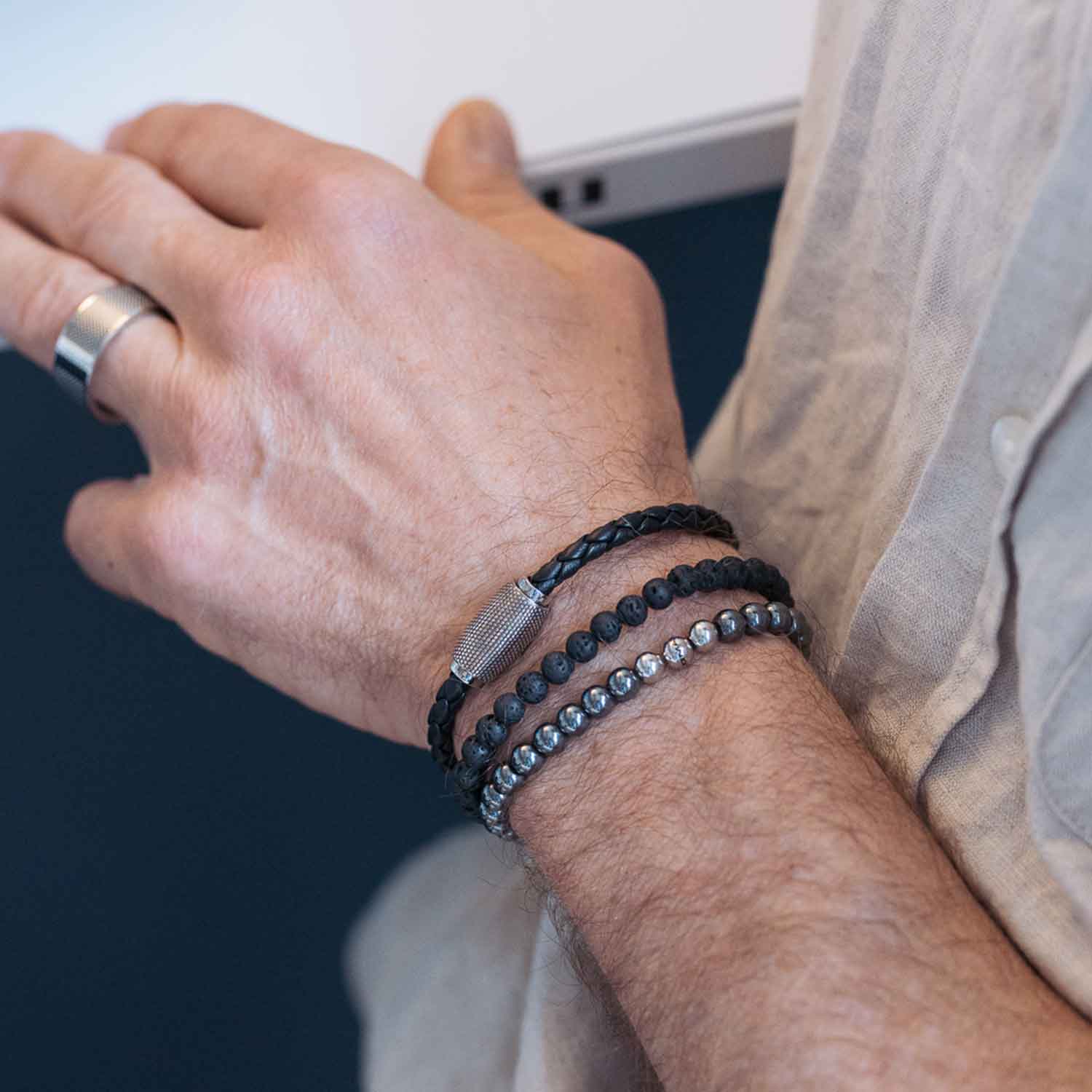 Gesamtansicht eines schwarzen Perlenarmbandes aus echten Lavaperlen mit drei antiallergenen Edelstahlperlen.