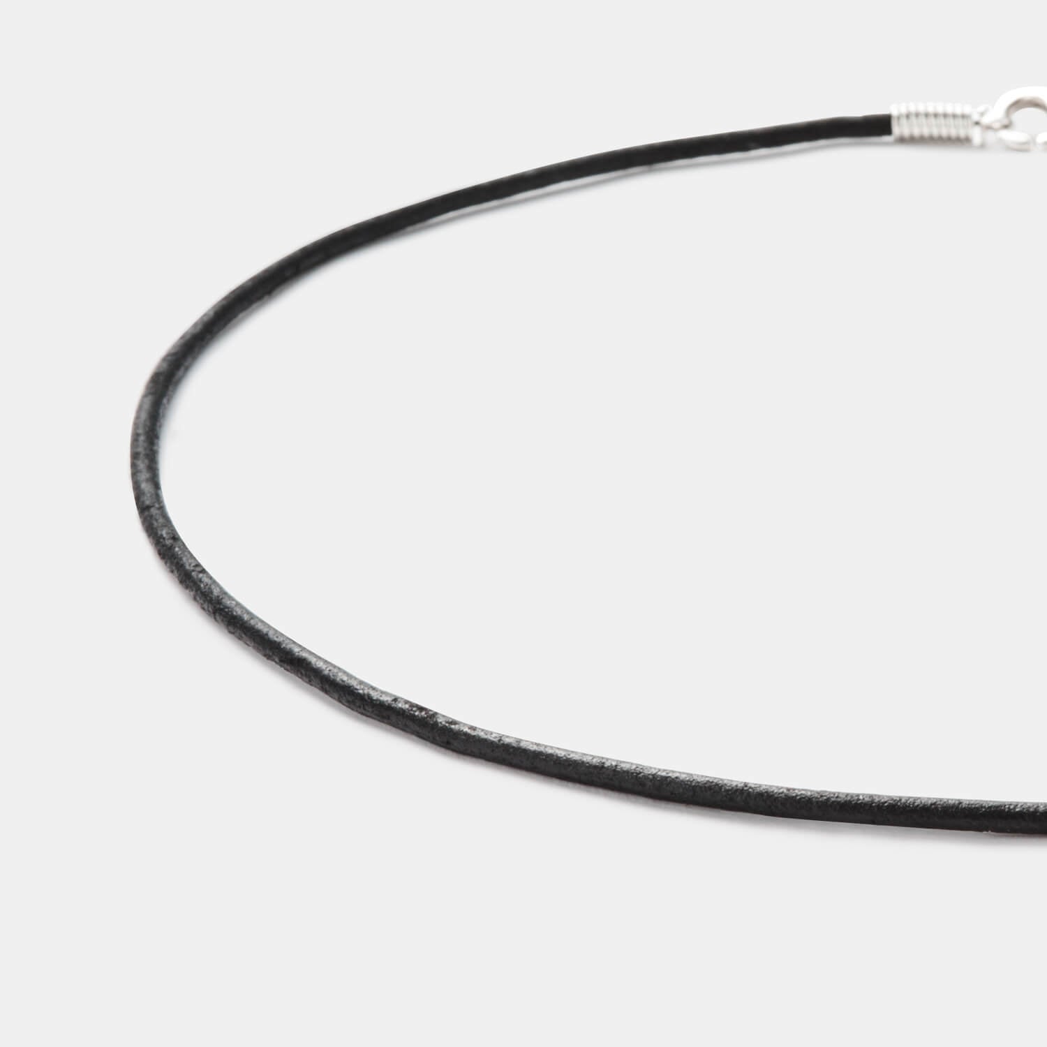 Detailansicht eines runden, schwarzen Lederbandes mit Karabinerverschluss aus antiallergenem Edelstahl von MONOMANIA.
