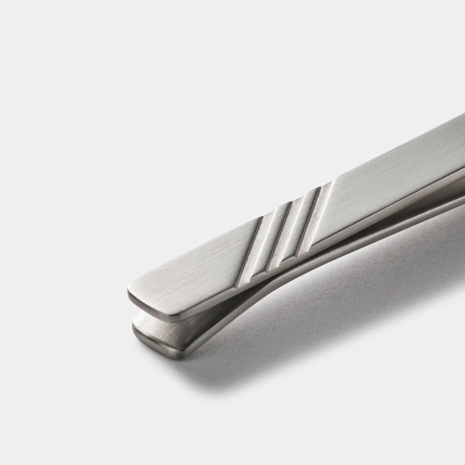 Detailansicht einer silberfarbenen Krawattennadel aus antiallergenem Edelstahl mit eleganten Einschnitten von MONOMANIA.