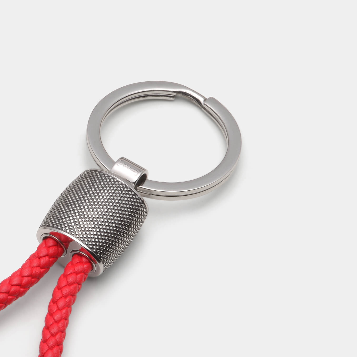 Gesamtansicht eines Schlüsselanhängers aus antiallergenem Edelstahl mit Punkterelief und roter Lederschlaufe von MONOMANIA.