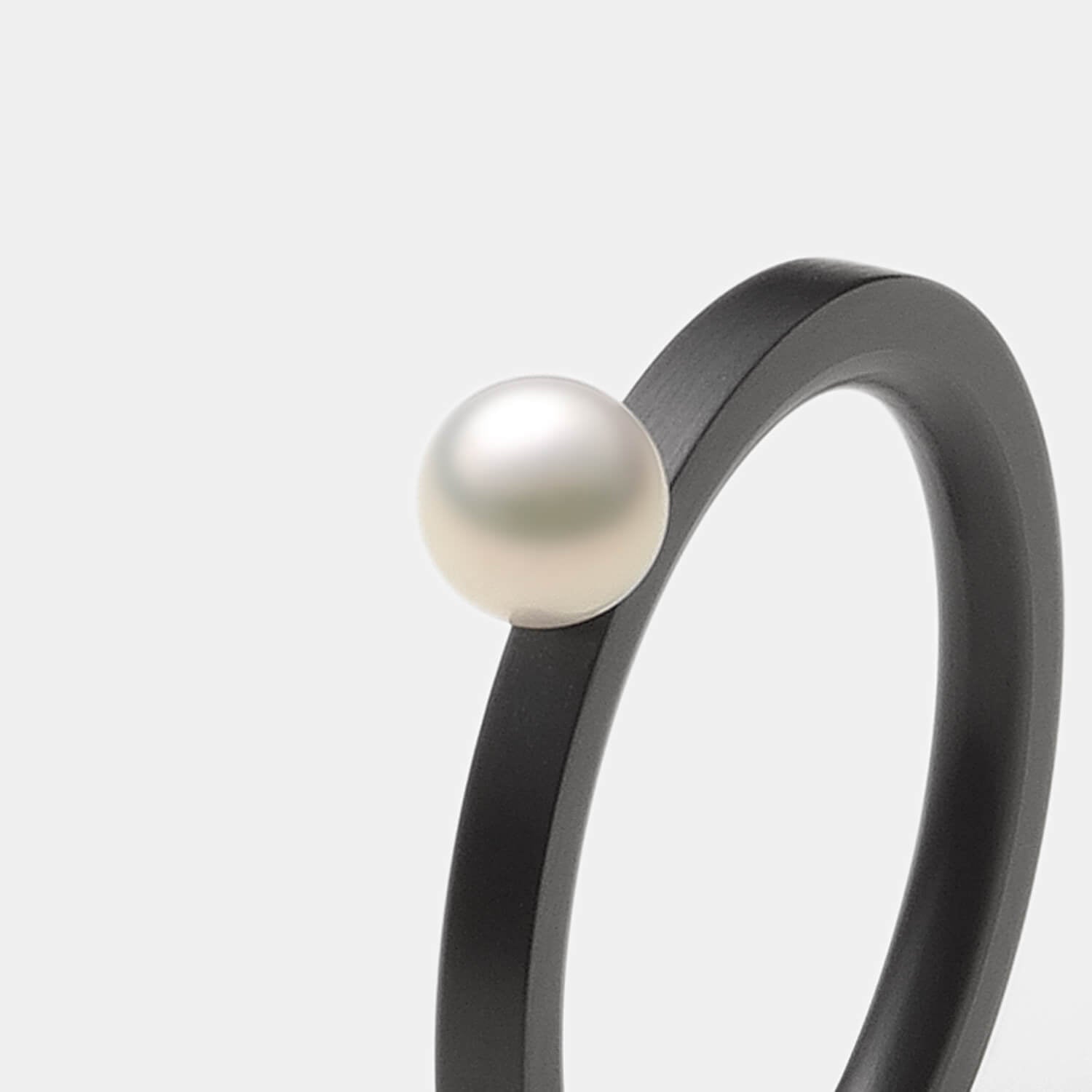 Gesamtansicht eines schmalen, schwarzen  Edelstahl-Rings mit echter, weißer Süßwasserperle von MONOMANIA.