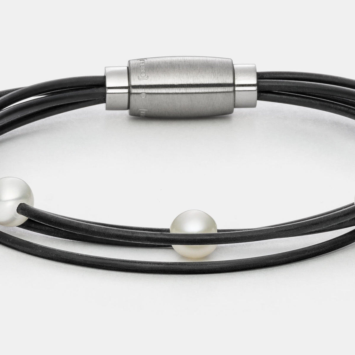 Gesamtansicht des modernen Armbandes mit echten, weißen Süßwasserperlen auf einem vierreihigen Kautschukband von MONOMANIA.