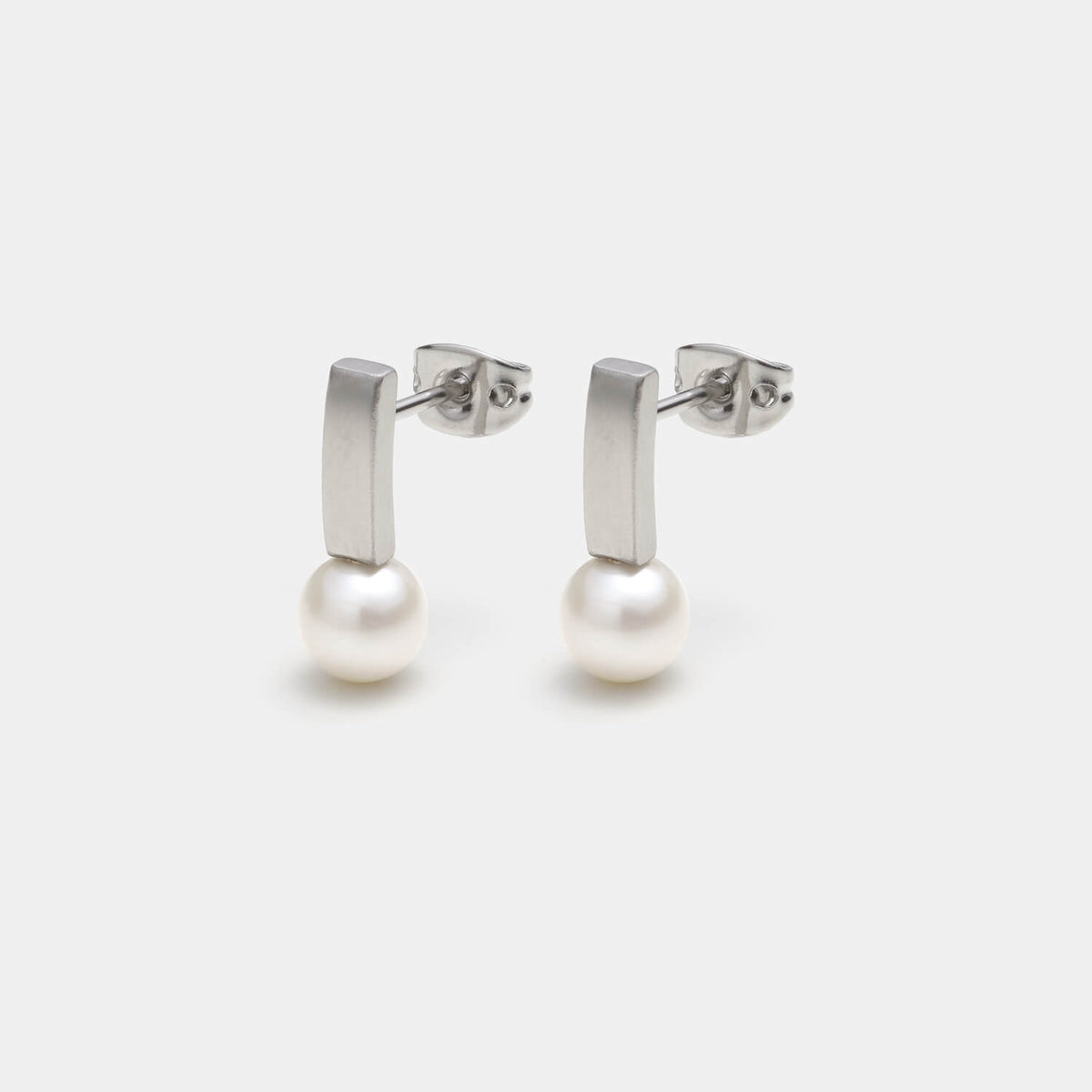 Perspektivische Ansicht der Pearl´s Kiss Ohrstecker aus gebürstetem, antiallergenen Edelstahl und einer gesetzten weißen Süßwasserperle von MONOMANIA.