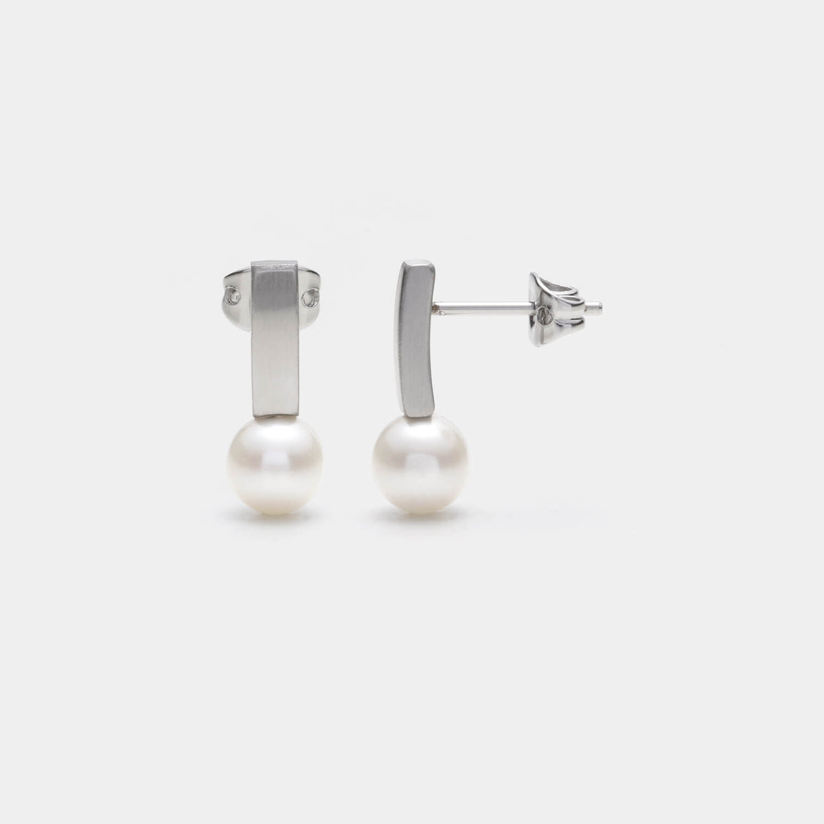 Perspektivische Ansicht der Pearl´s Kiss Ohrstecker aus gebürstetem, antiallergenen Edelstahl und einer gesetzten weißen Süßwasserperle von MONOMANIA.